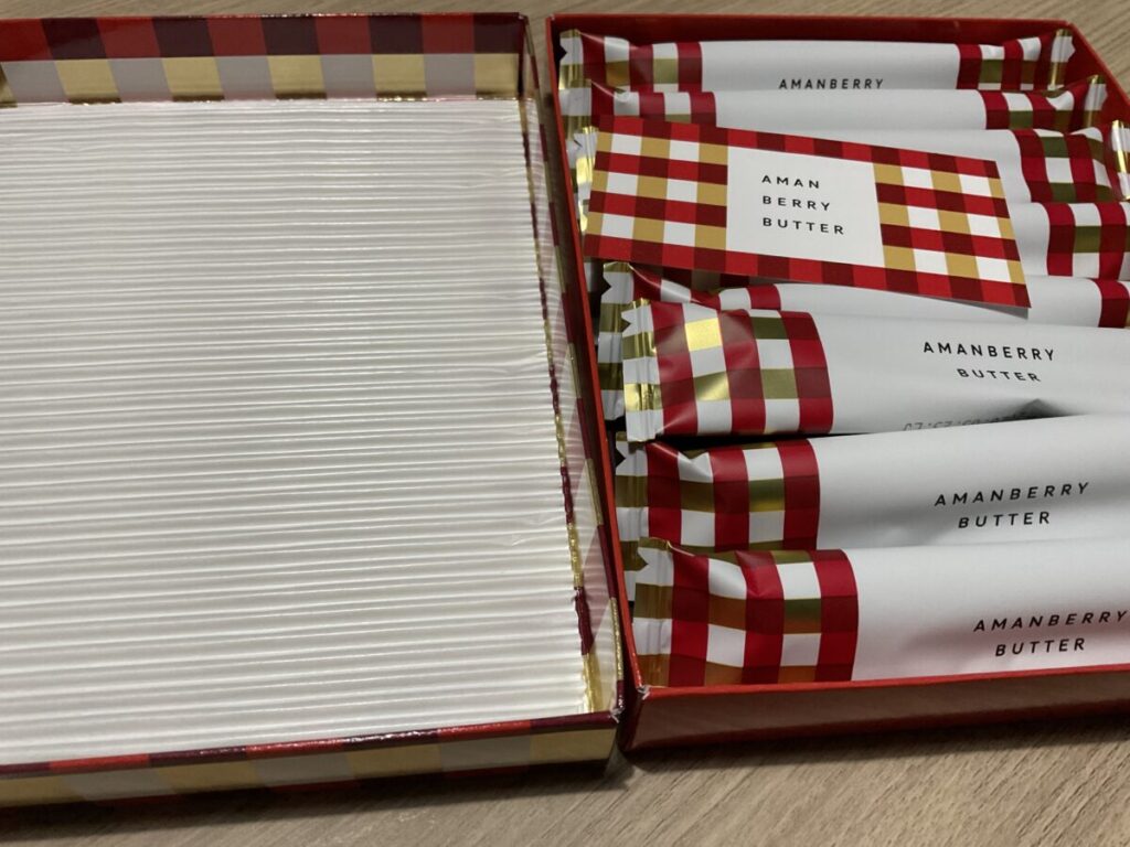 箱を開けた状態のアマンベリーバターと個包装されたお菓子。