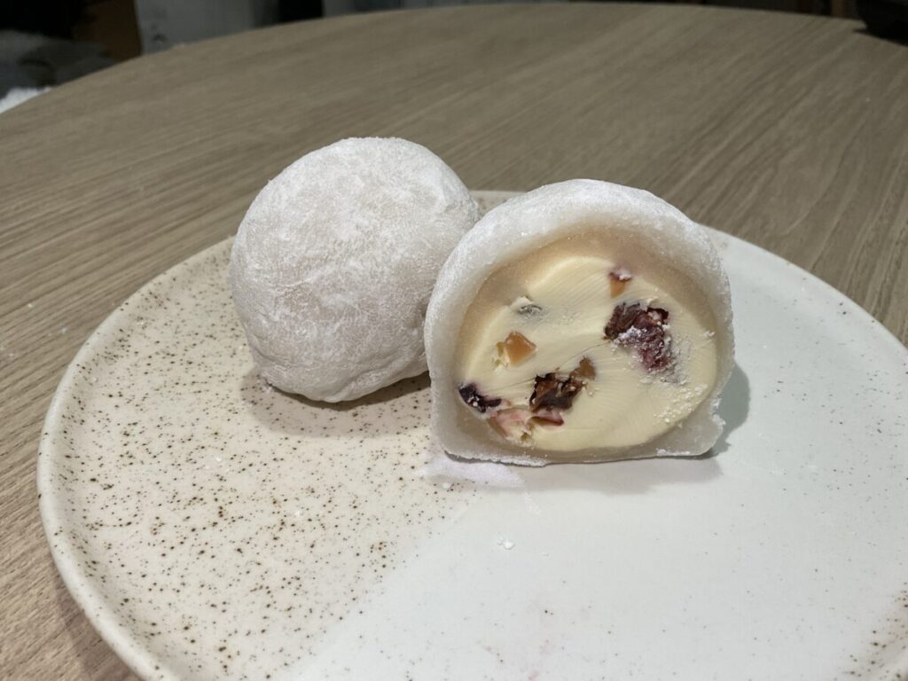 「クリームチーズ大福」の断面。白いクリームチーズの中にドライフルーツが入っているのが見える。