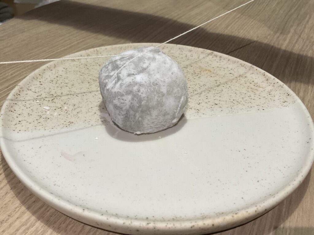 大福を糸で切るための準備。お皿の上の大福に紐をクロスさせてセットした状態。