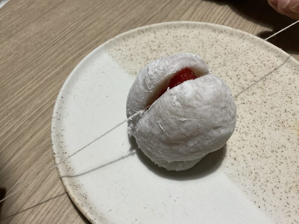 付属の「お福分け紐」を使って、いちご大福を半分にカットしている瞬間の様子。