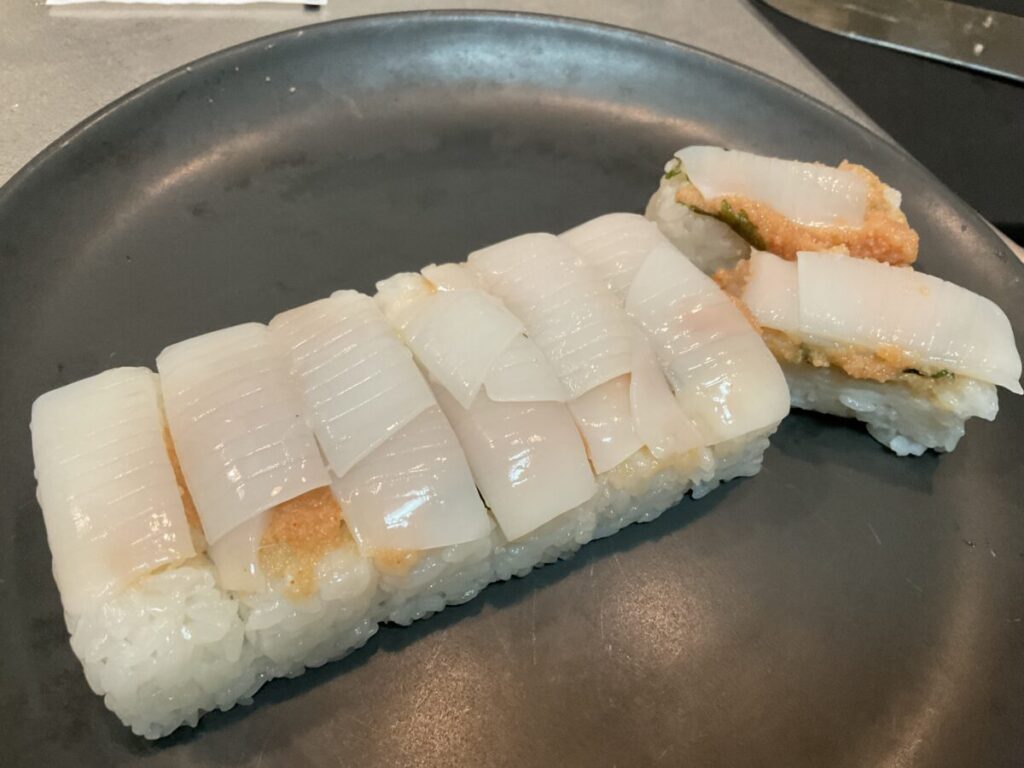 寿司を横にして見せた、シャリとイカの間に挟まれたたっぷりの明太子と大葉の断面。