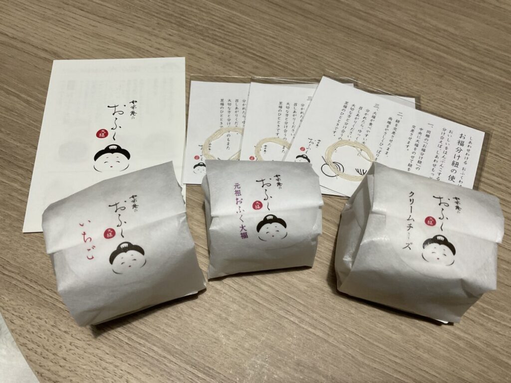 個包装された3種類の大福（いちご、元祖、クリームチーズ）と、付属のカット用紐（お福分け紐）の説明書一式。