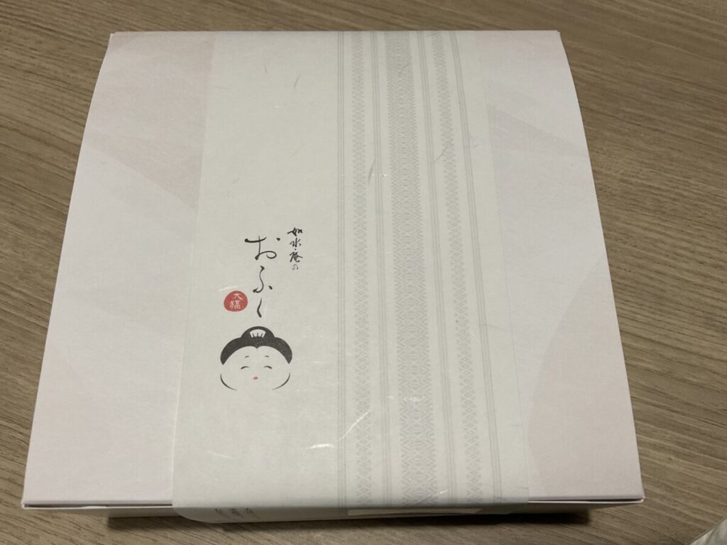 如水庵「おふく大福」のギフト用化粧箱。白い箱にお多福のロゴと帯がデザインされている。