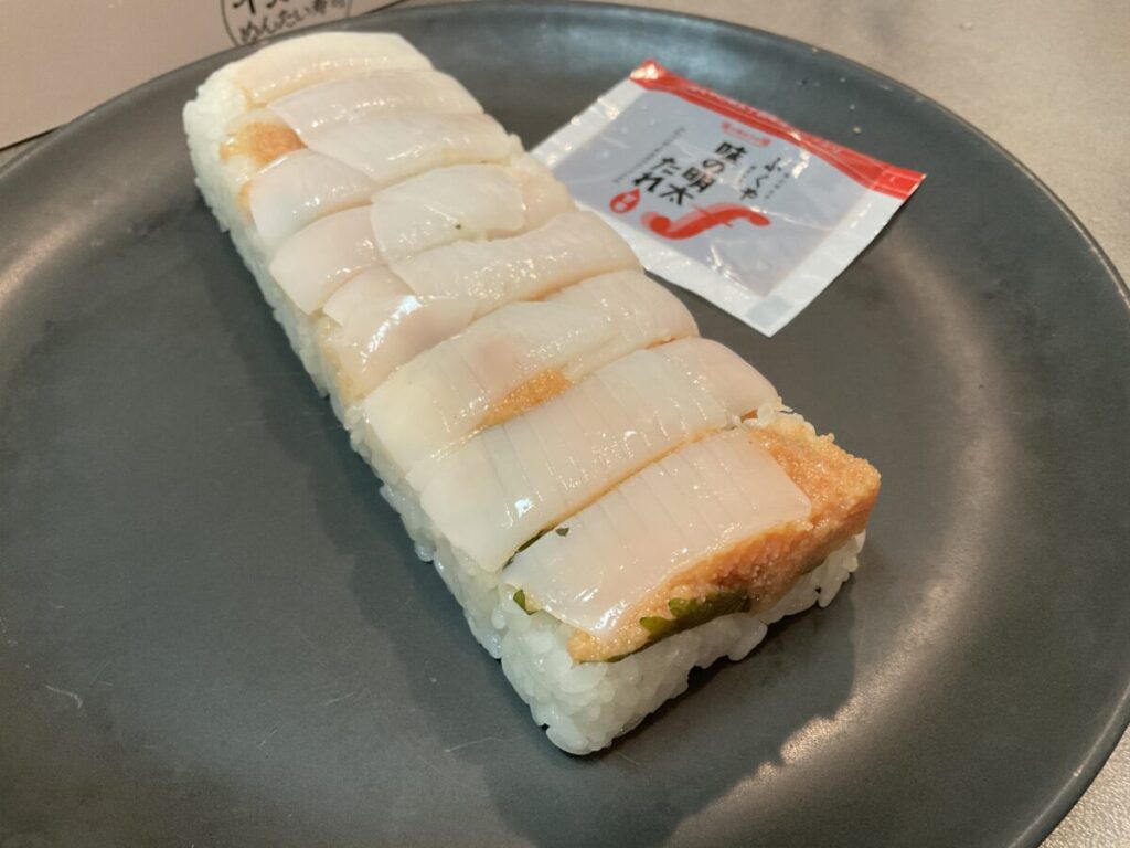 お皿に盛り付けた寿司と、付属している「味の明太たれ」の小袋。