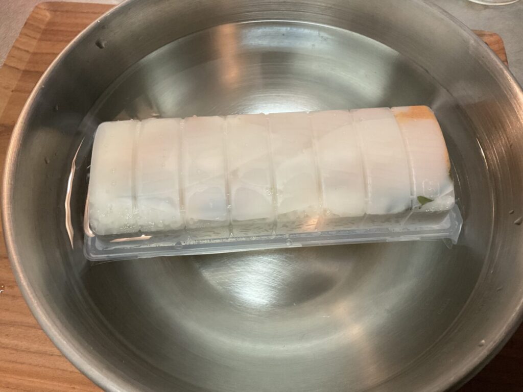 水中で解凍が進み、イカのネタが見えている状態のパック寿司。